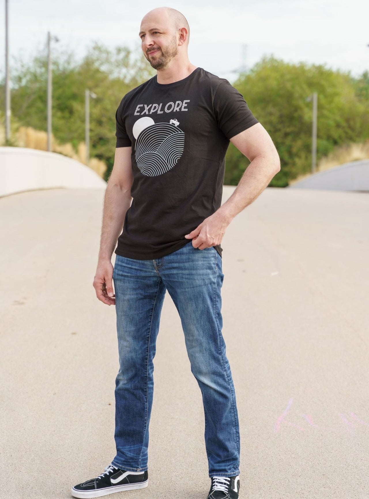 A head to toe shot of a tall skinny guy wearing a tall black graphic t-shirt.