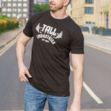 A tall skinny guy, hand in pocket, wearing a tall slim graphic t-shirt.