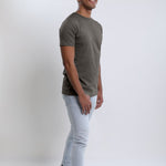 A head to toe shot of a tall slim guy in a studio and wearing a dark grey medium tall slim t-shirt.