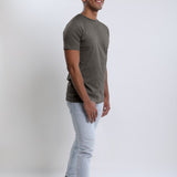 A head to toe shot of a tall slim guy in a studio and wearing a dark grey medium tall slim t-shirt.