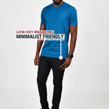 A head to toe shot of a tall slim guy in a studio wearing an azure large tall slim t-shirt and smiling.