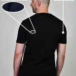 A shot from behind of a tall and slim guy in a studio and wearing a black XL tall slim t-shirt.