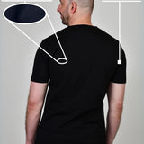 A shot from behind of a tall and slim guy in a studio and wearing a black XL tall slim t-shirt.