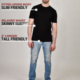 A head to toe shot of a tall muscular guy in a studio and wearing a black XL tall t-shirt.