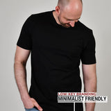 A tall athletic guy standing in a studio and wearing a black XL tall t-shirt, looking down at the Just Tall monogram logo.