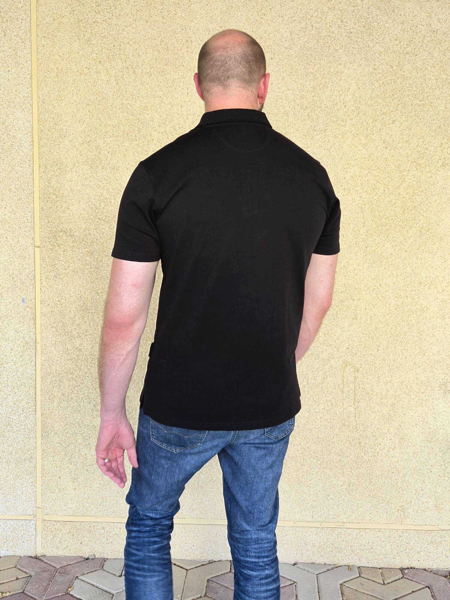 A shot from behind of a tall slim man wearing an XL tall zip polo shirt.