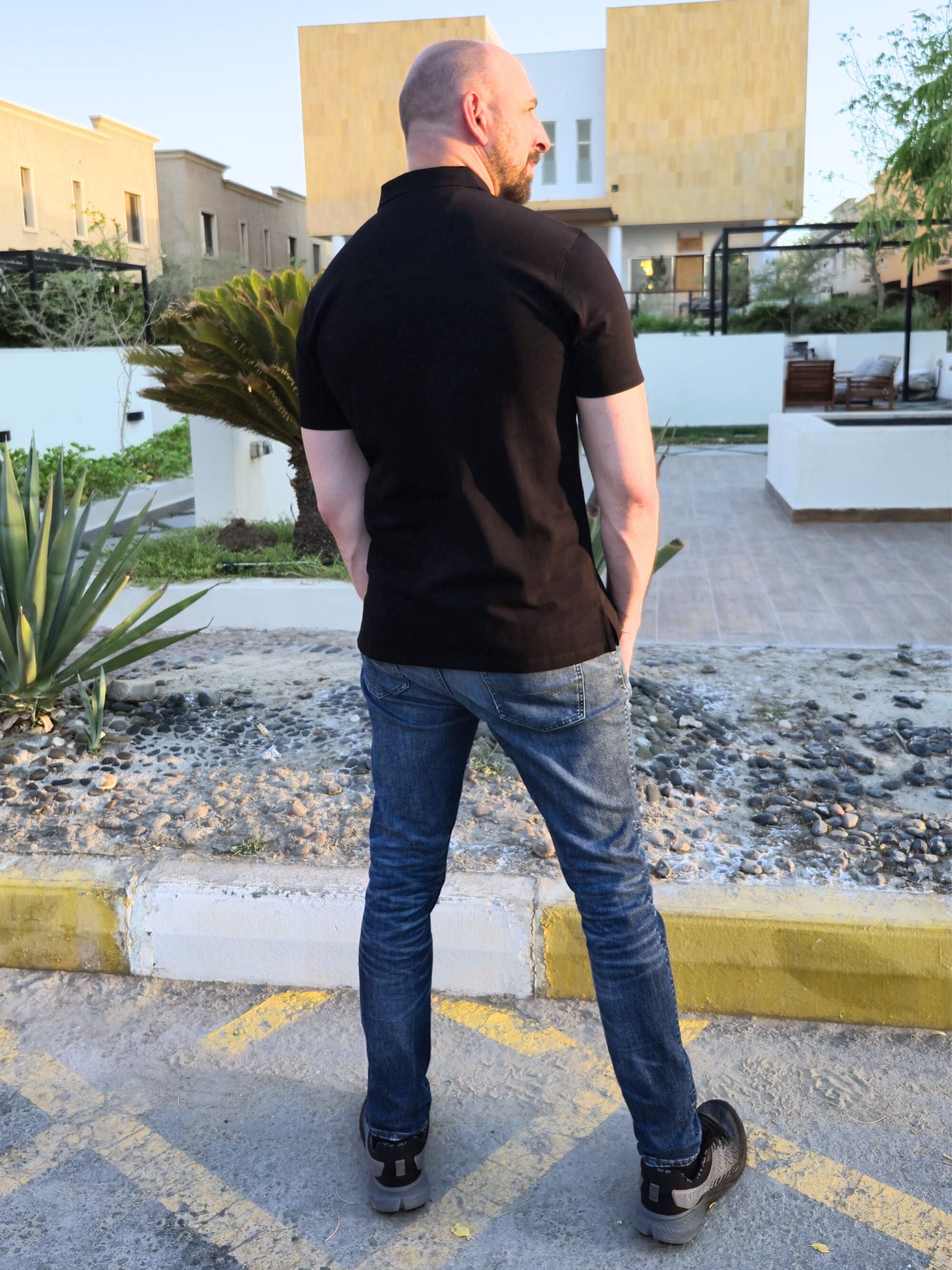 A shot from behind of a tall slim man wearing an XL tall black zip polo shirt.