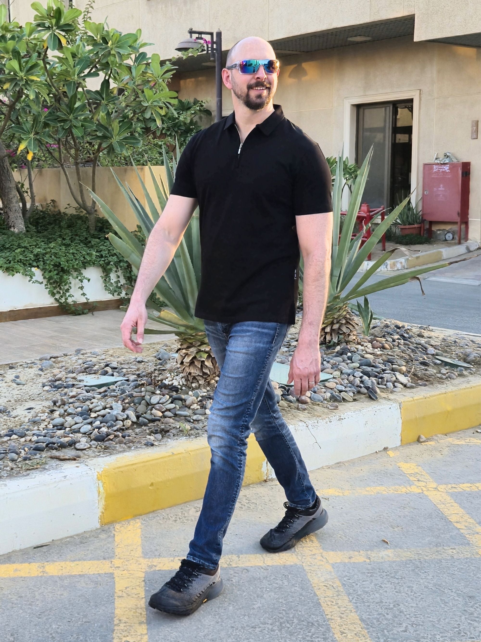 A tall slim man wearing an XL tall black zip polo shirt.