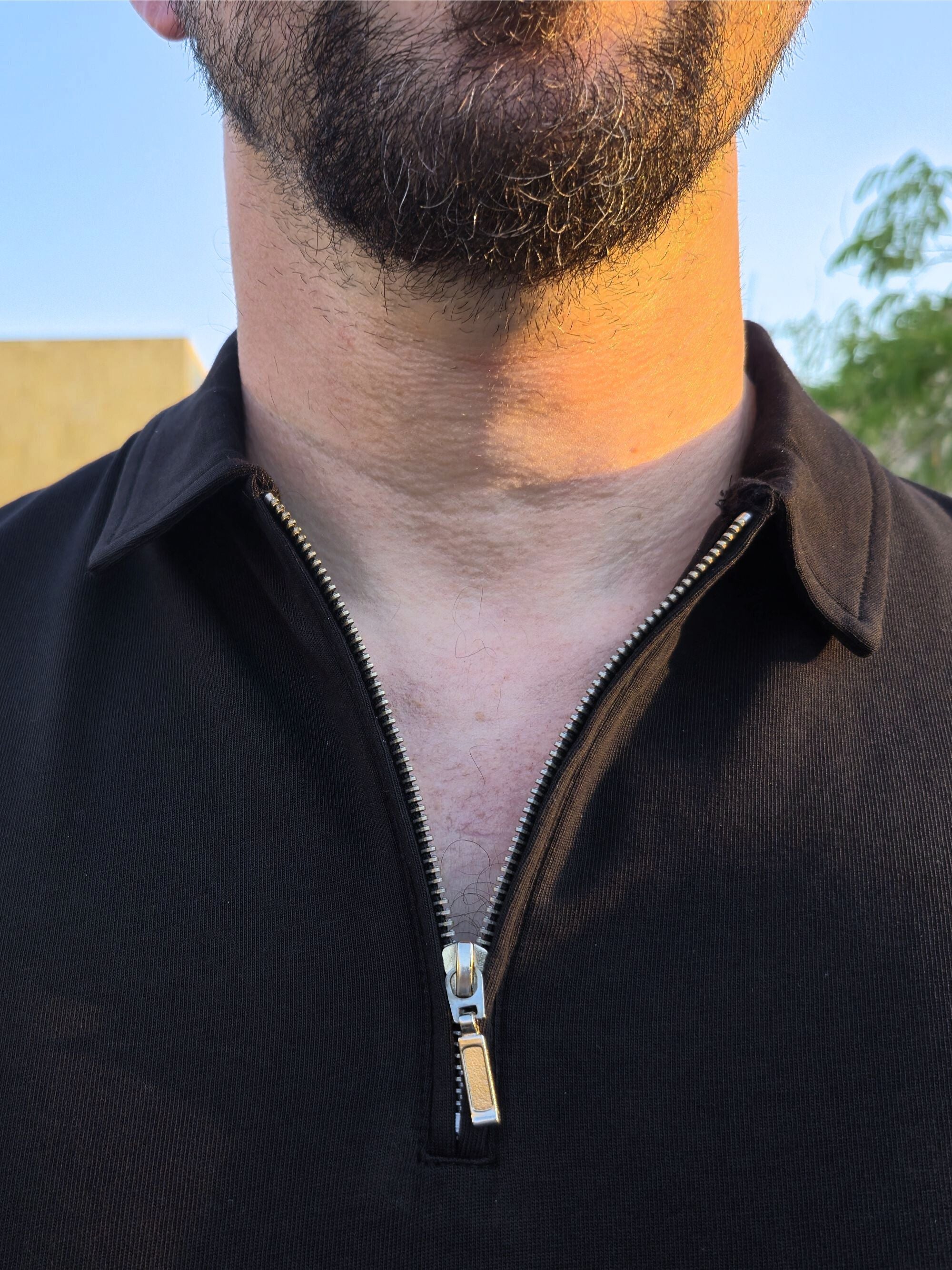 A close up of the self fabric collar of an XL tall black zip polo.