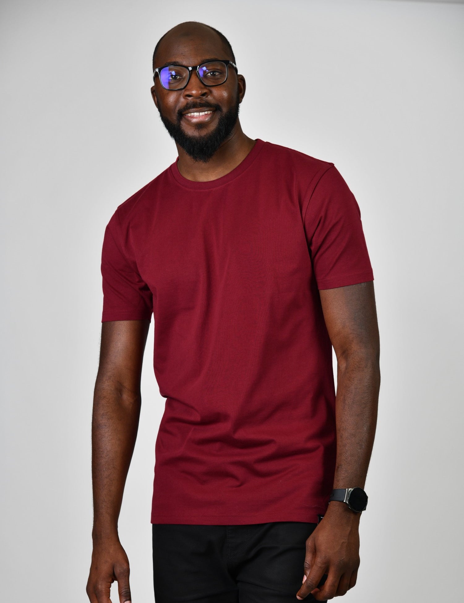A tall and slim man in the studio standing in front of a light background. The smiling model is wearing an extra long slim cabernet t-shirt in a size large. The tall cabernet t-shirt features a 3" longer body, 100% organic cotton, and is soft & preshrunk. The cabernet  t-shirt is ideal for tall slim men 6'2"+.