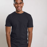 A tall and slim man in the studio standing in front of a light background. The smiling model is wearing an extra long slim charcoal t-shirt in a size medium. The tall charcoal t-shirt features a 3" longer body, 100% organic cotton, and is soft & preshrunk. The charcoal t-shirt is ideal for tall slim men 6'2"+.