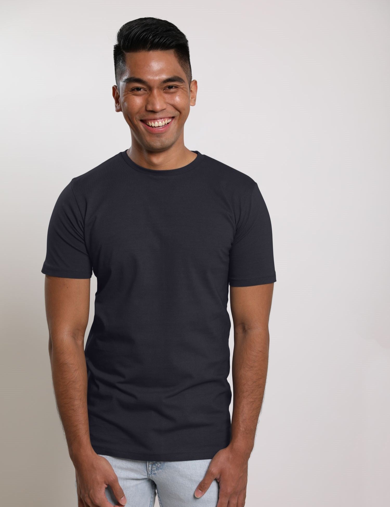 A tall and slim man in the studio standing in front of a light background. The smiling model is wearing an extra long slim charcoal t-shirt in a size medium. The tall charcoal  t-shirt features a 3" longer body, 100% organic cotton, and is soft & preshrunk. The charcoal t-shirt is ideal for tall slim men 6'2"+.