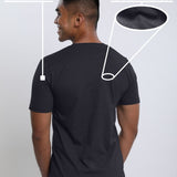 A shot from behind of a tall and slim guy in a studio and wearing a charcoal medium tall slim t-shirt.
