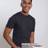 An upper body shot of a tall slim guy in a studio and wearing a charcoal medium tall t-shirt, hand in pocket.