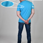 A shot from behind of a tall and athletic guy in a studio and wearing a cyan XL tall slim t-shirt.