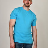 An upper body shot of a tall athletic guy in a studio and wearing a cyan extra large tall slim t-shirt.