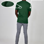 A shot from behind of a tall and slim guy in a studio and wearing a dark green large tall slim t-shirt.