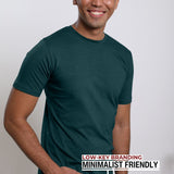 An upper body shot of a tall slim guy in a studio and wearing a dark teal medium tall t-shirt, hand in pocket.