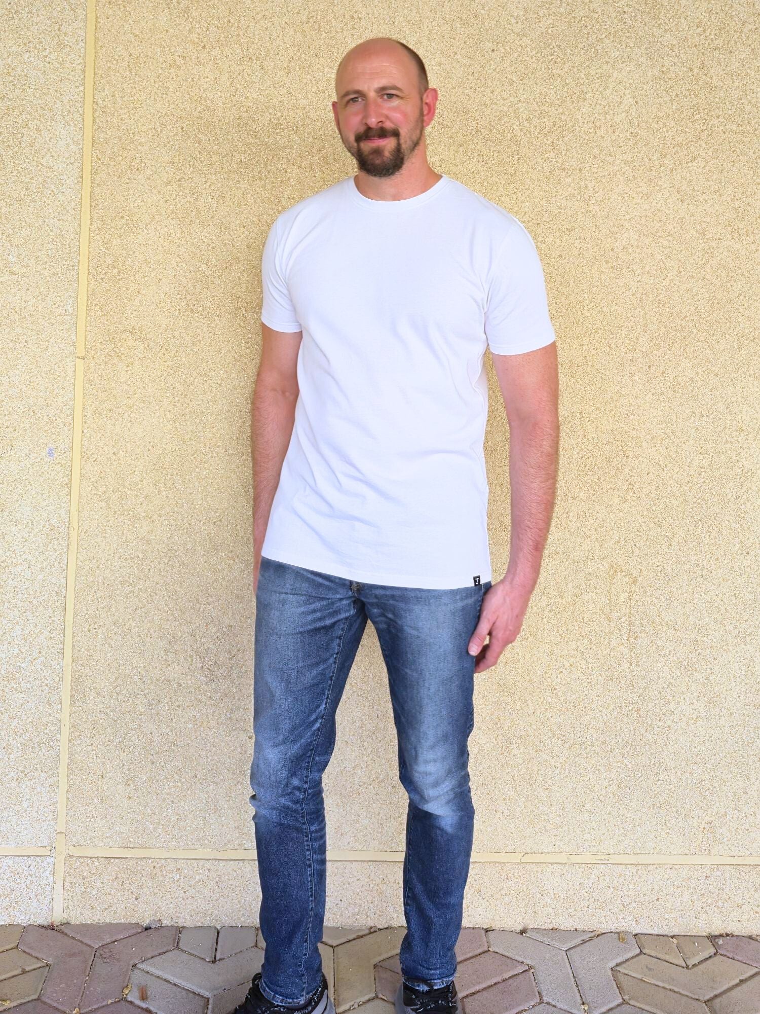 A head to toe shot of a tall slim guy wearing an XL tall white heavyweight t-shirt.