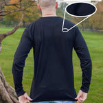 A shot from behind of a tall slim guy in a park wearing an extra long sleeve long sleeve tall t-shirt in black.
