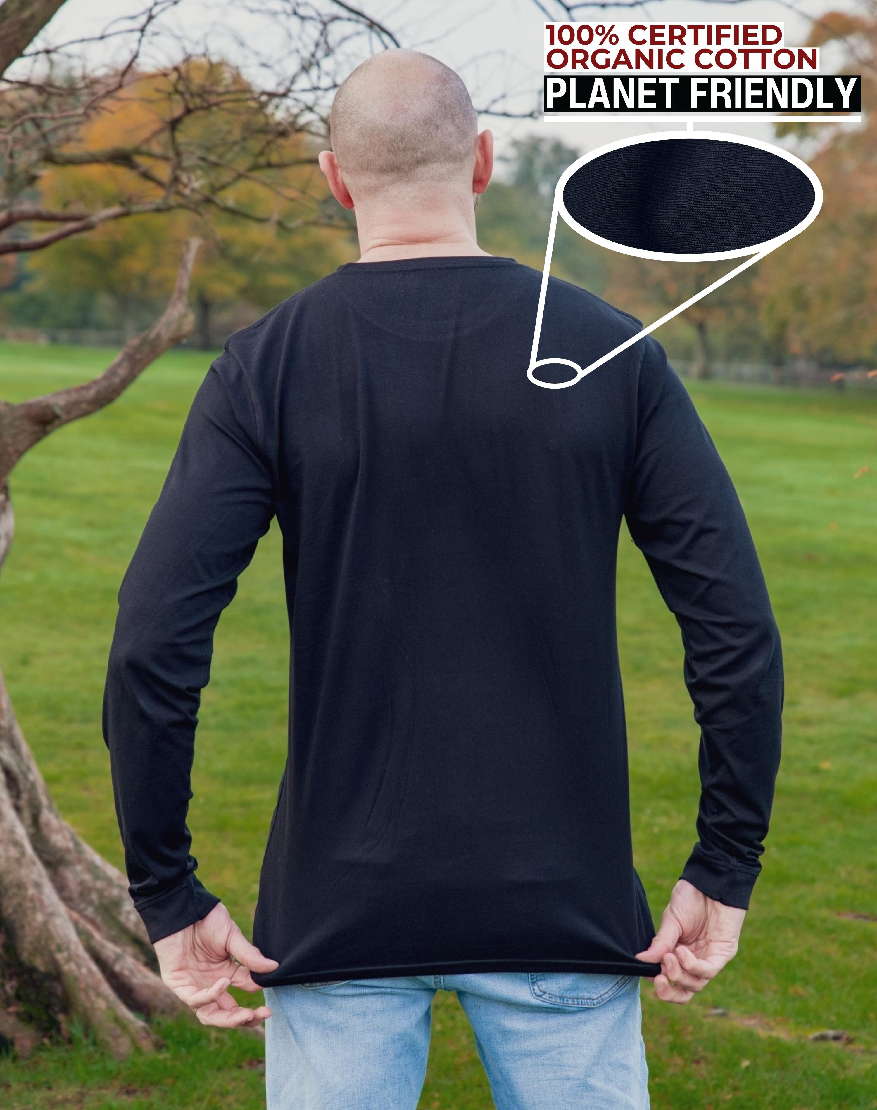 A shot from behind of a tall slim guy in a park wearing an extra long sleeve long sleeve tall t-shirt in black.