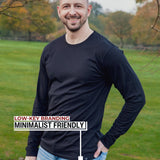 An upper body shot of a tall athletic guy standing in a park wearing a black extra long tall long sleeve t-shirt and showing the Just Tall minimalist monogram logo.