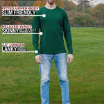 A head to toe shot of a tall athletic guy in a park wearing a dark green long sleeve tall t-shirt.