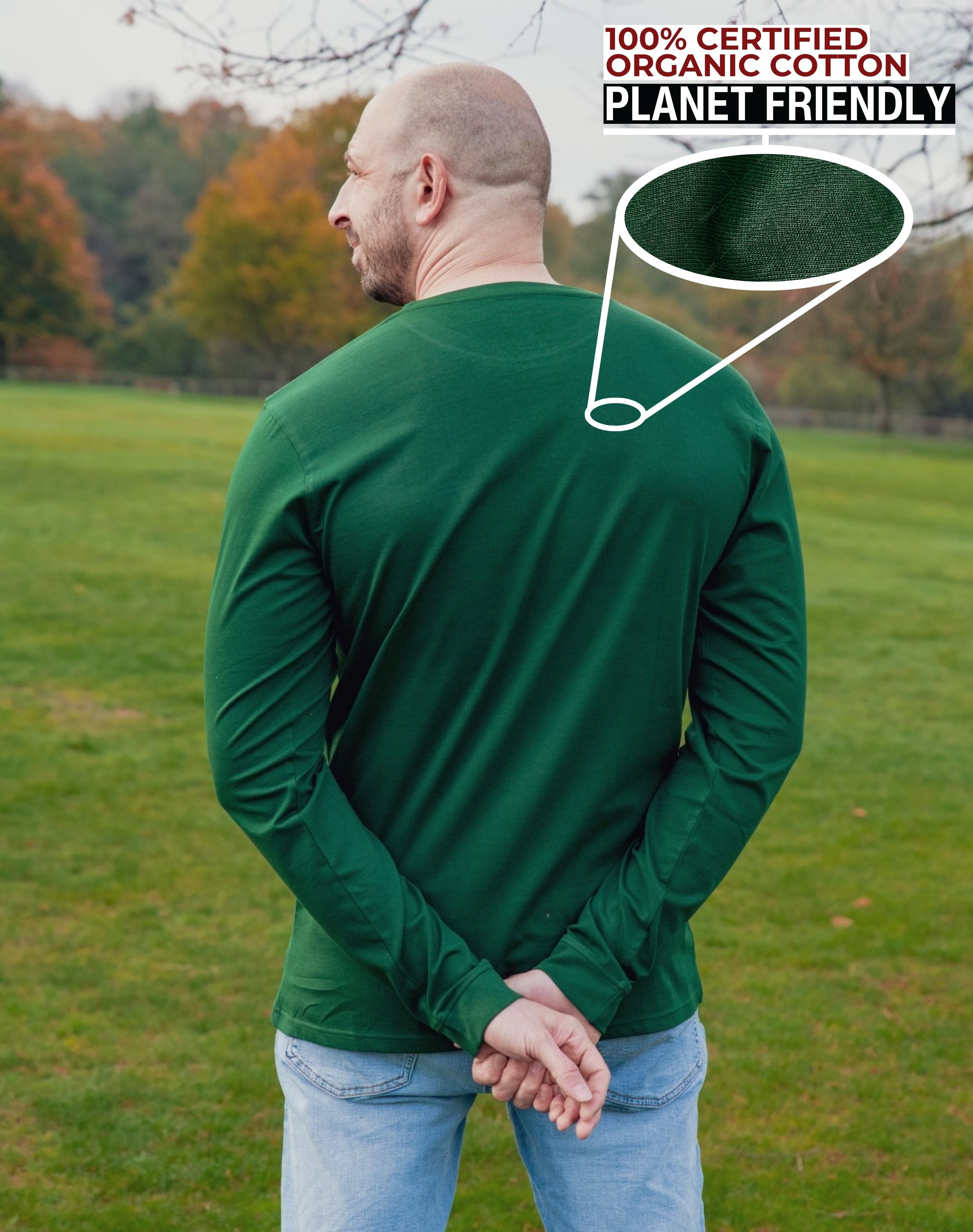 A shot from behind of a tall slim guy in a park wearing an extra long sleeve long sleeve tall t-shirt in green.