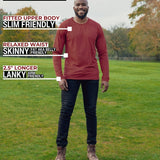 A head to toe shot of a tall athletic guy in a park wearing a dark orange long sleeve tall t-shirt.