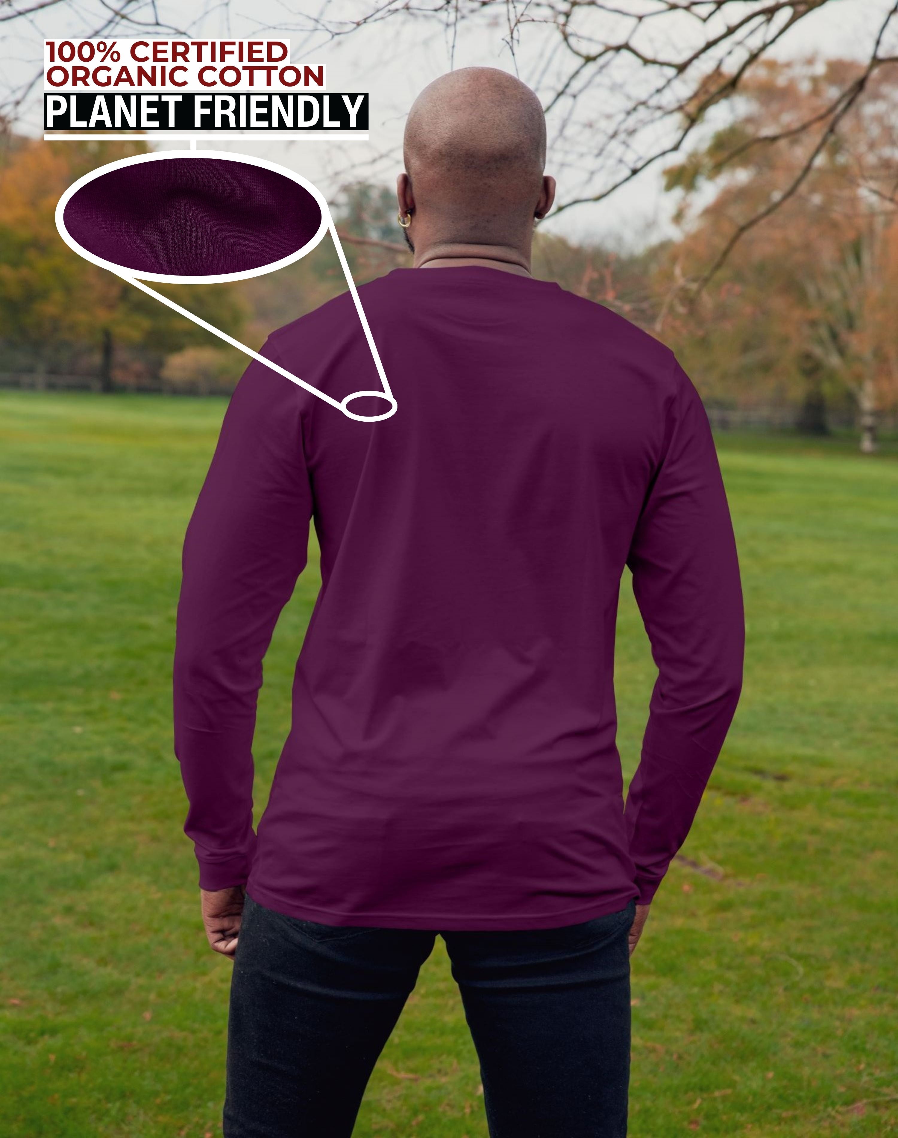 A shot from behind of a tall slim guy in a park wearing an extra long sleeve long sleeve tall t-shirt in dark purple.