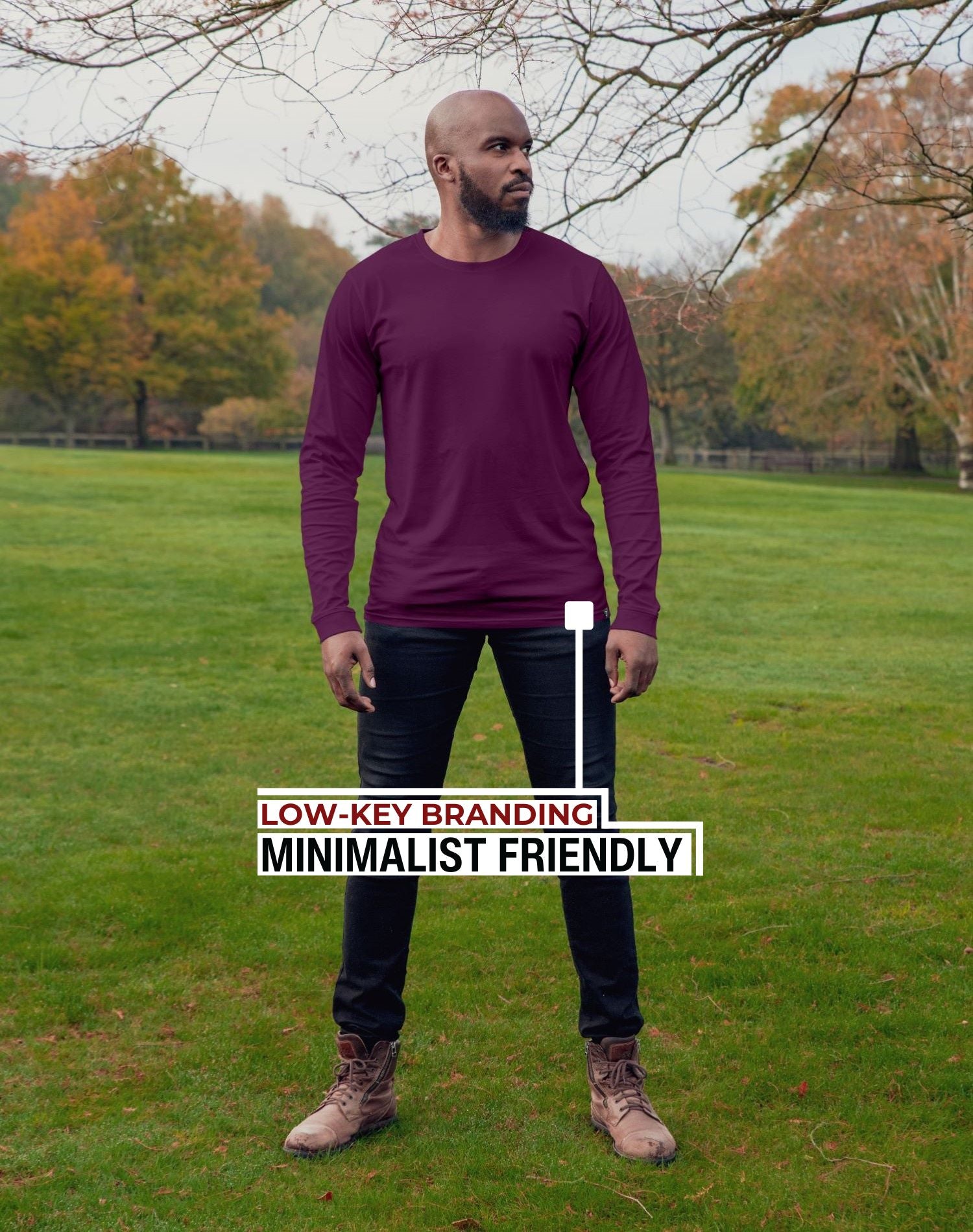 An upper body shot of a tall athletic guy standing in a park wearing a dark purple extra long tall long sleeve t-shirt and showing the Just Tall minimalist monogram logo.