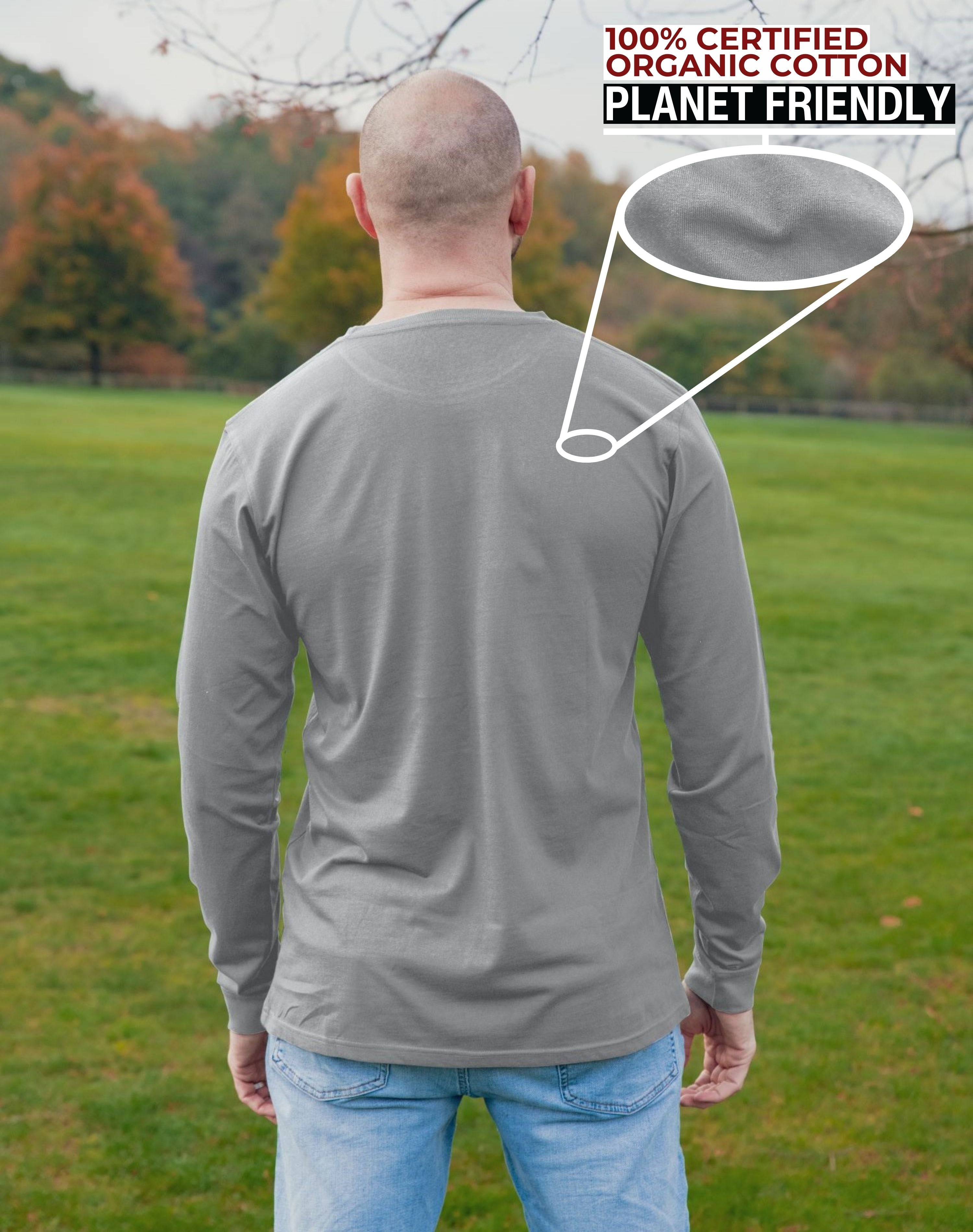 A shot from behind of a tall slim guy in a park wearing an extra long sleeve long sleeve tall t-shirt in light grey.