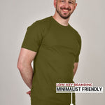 A tall athletic guy standing in a studio and wearing ab olive XL tall t-shirt, smiling and hands behind back.