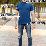 A head to toe shot of a tall athletic man in a park wearing a navy XL tall polo shirt and smiling.