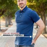 An upper body shot of a tall athletic guy in a park and wearing an XL tall slim navy polo shirt and showing the minimal Just Tall flag logo near the bottom of the side seam.
