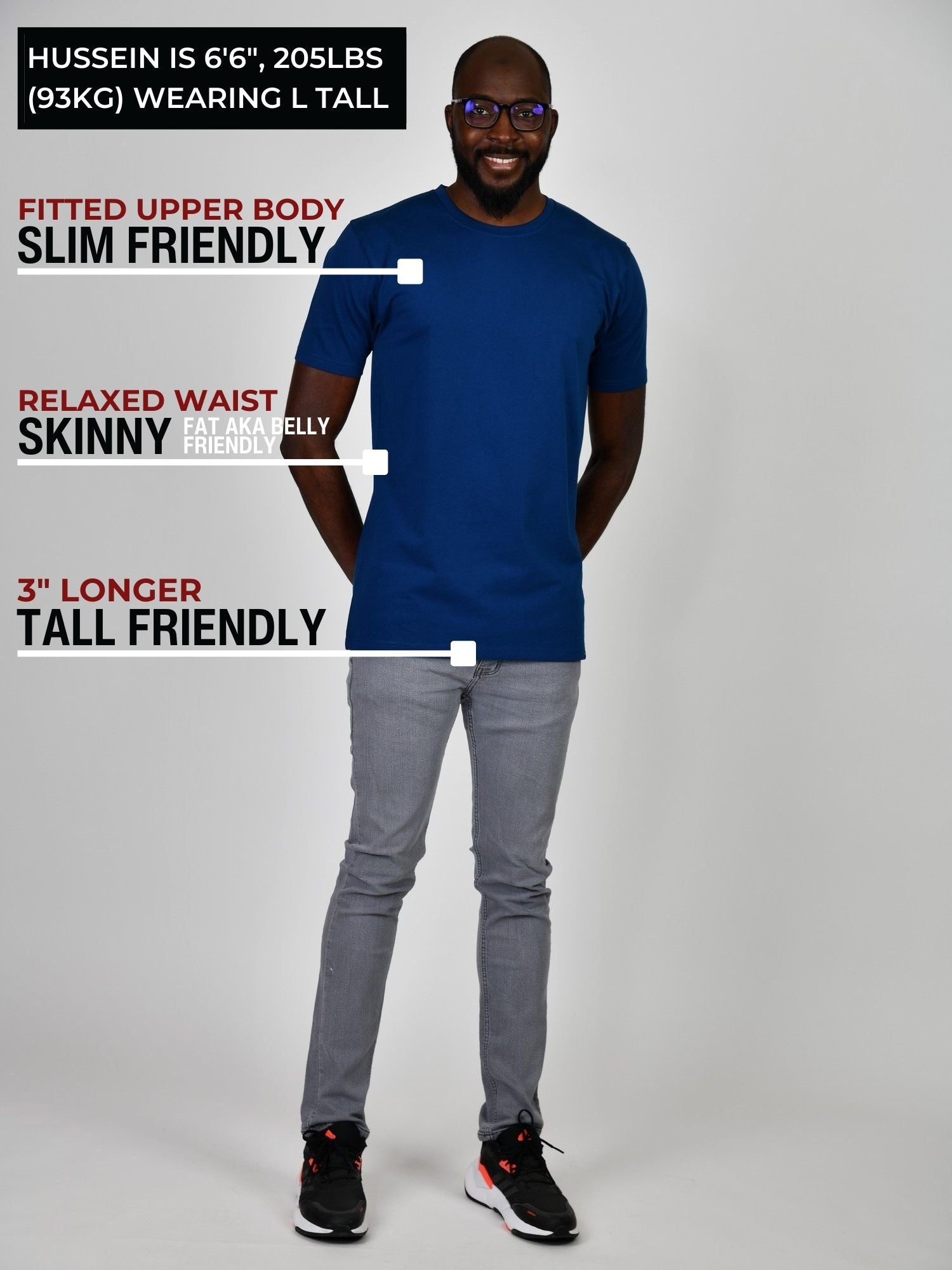 A head to toe shot of a tall slim guy in a studio and wearing a navy large tall slim t-shirt.