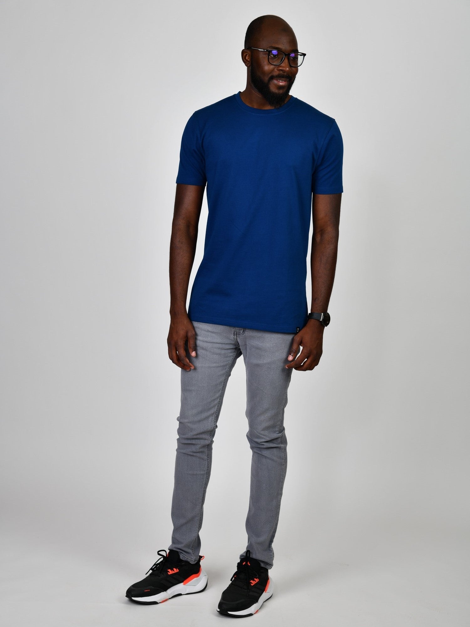 A head to toe shot of a tall slim guy in a studio and wearing a navy large tall slim t-shirt.