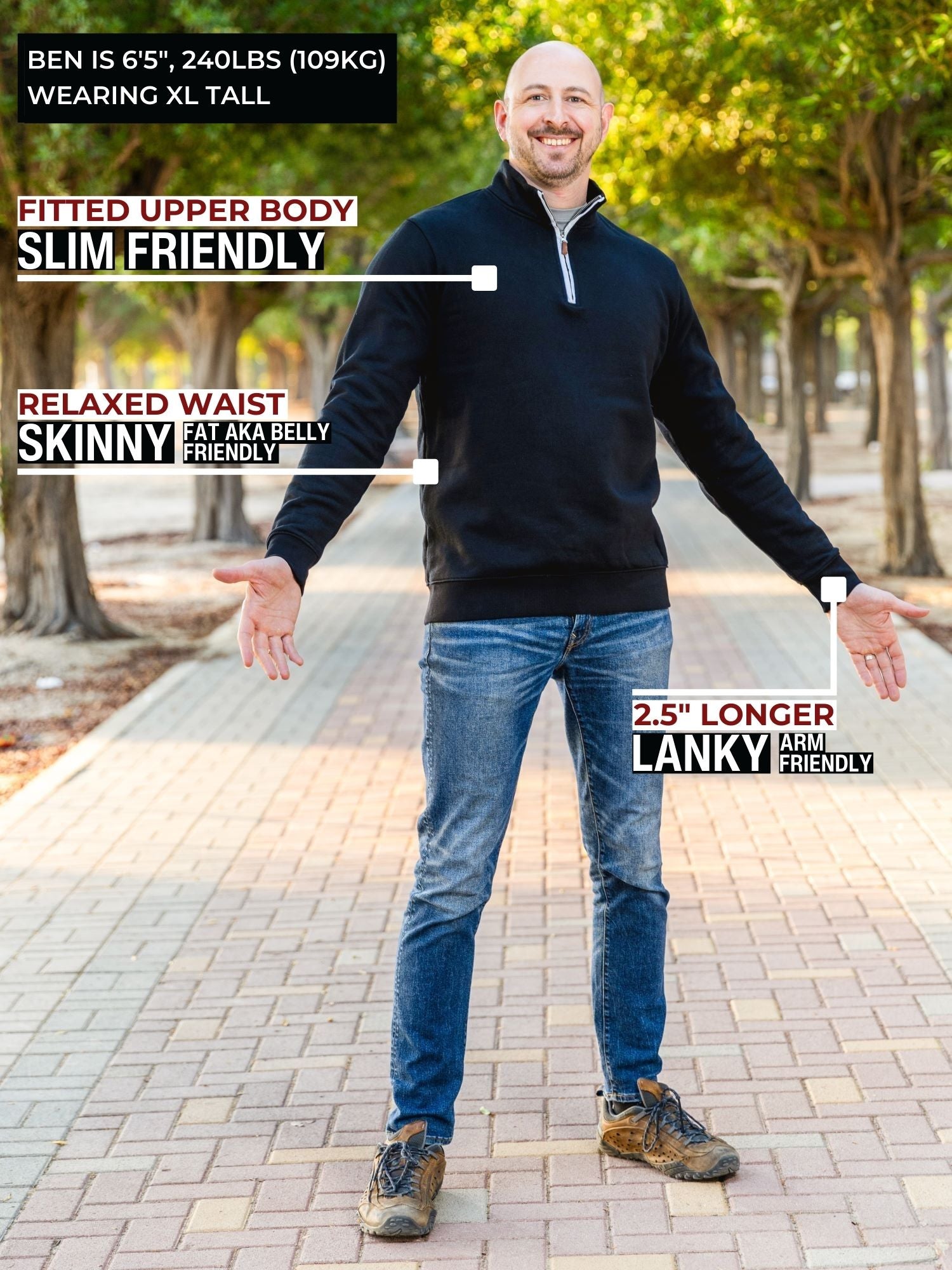 A head to toe shot of a tall athletic guy in a park wearing an XL tall extra long black quarter zip sweatshirt.