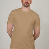 A tall and slim man in the studio standing in front of a light background. The smiling model is wearing an extra long slim tan t-shirt in a size XL. The tall tan t-shirt features a 3" longer body, 100% organic cotton, and is soft & preshrunk. The tan t-shirt is ideal for tall slim men 6'2"+.