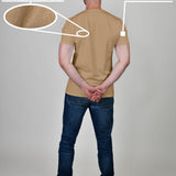 A shot from behind of a tall and athletic guy in a studio and wearing a tan XL tall slim t-shirt.