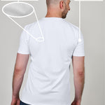 A shot from behind of a tall and slim guy in a studio and wearing a white XL tall slim t-shirt.
