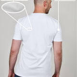 A shot from behind of a tall and slim guy in a studio and wearing a white XL tall slim t-shirt.