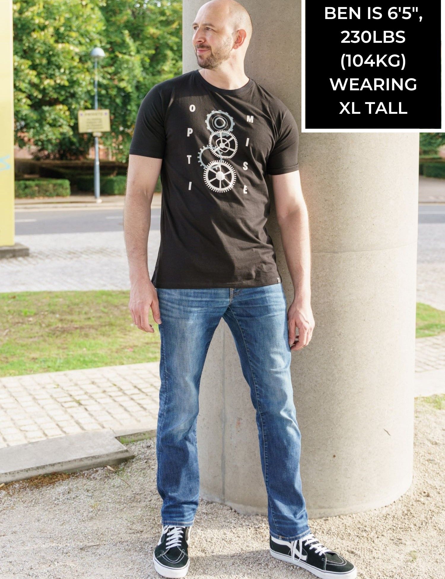 A tall slim guy wearing a tall slim graphic t-shirt in a park.
