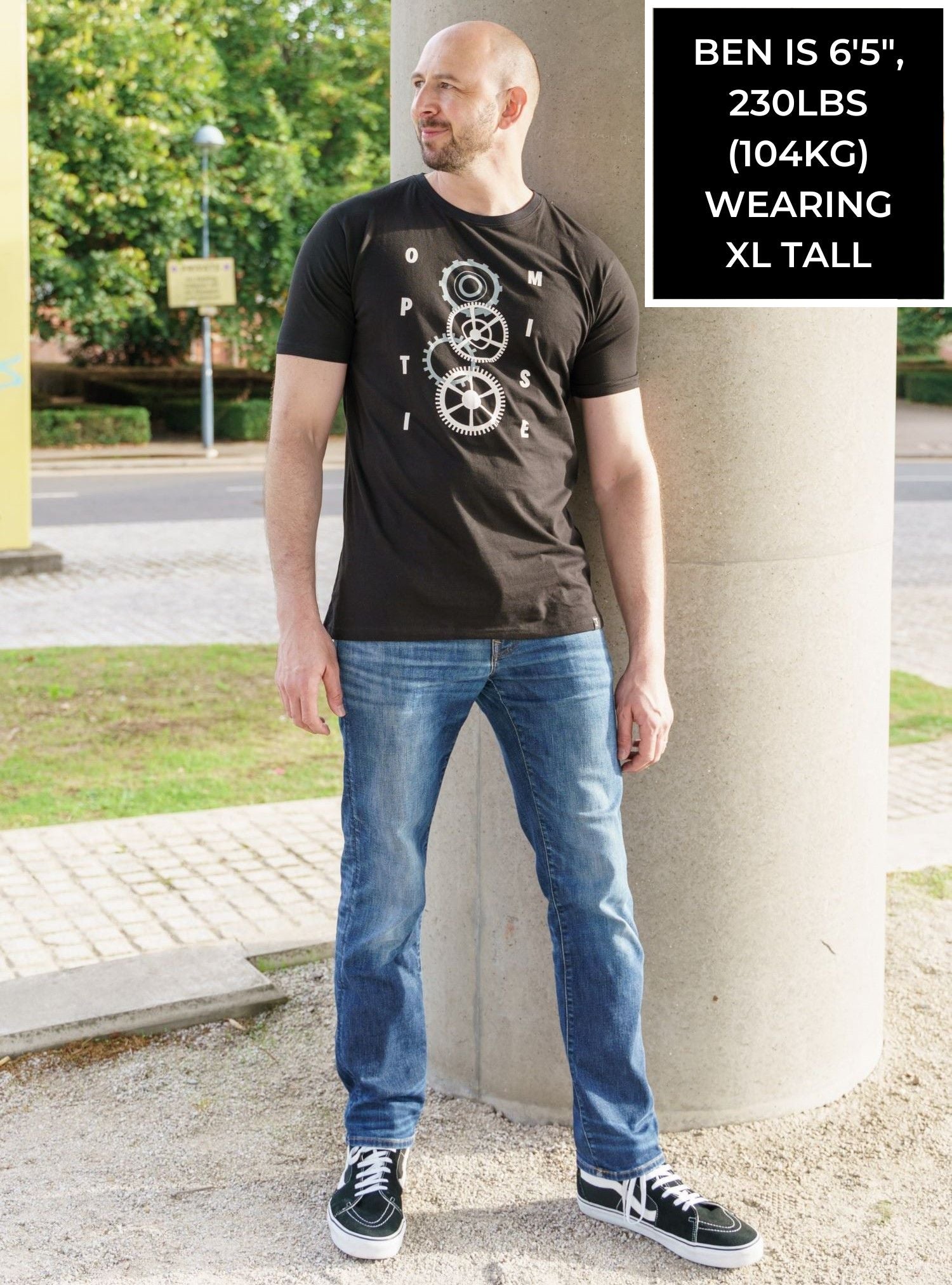 A tall slim guy wearing a tall slim graphic t-shirt in a park.