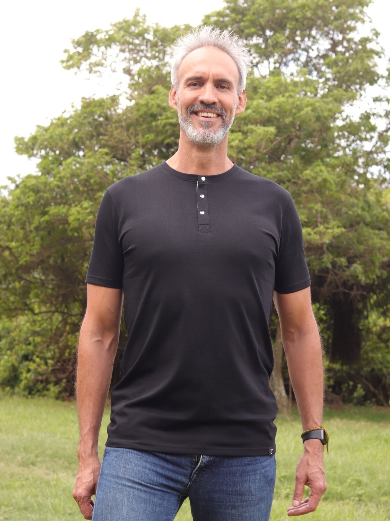 A tall skinny guy wearing a tall black henley shirt and laughing.