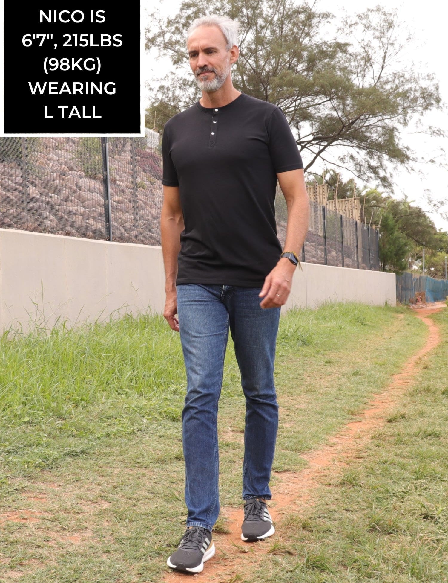 A head to toe shot of a tall skinny guy wearing a tall black henley shirt.