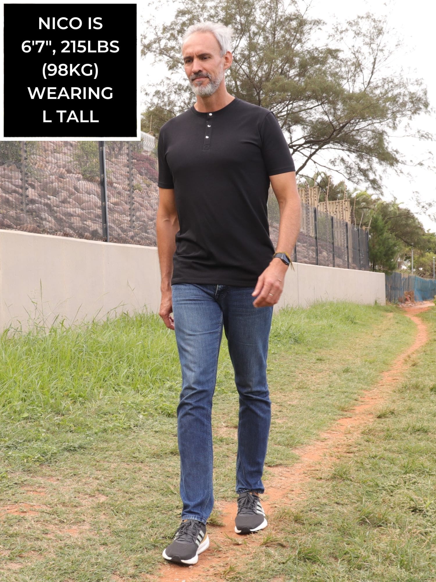 A head to toe shot of a tall skinny guy wearing a tall black henley shirt.