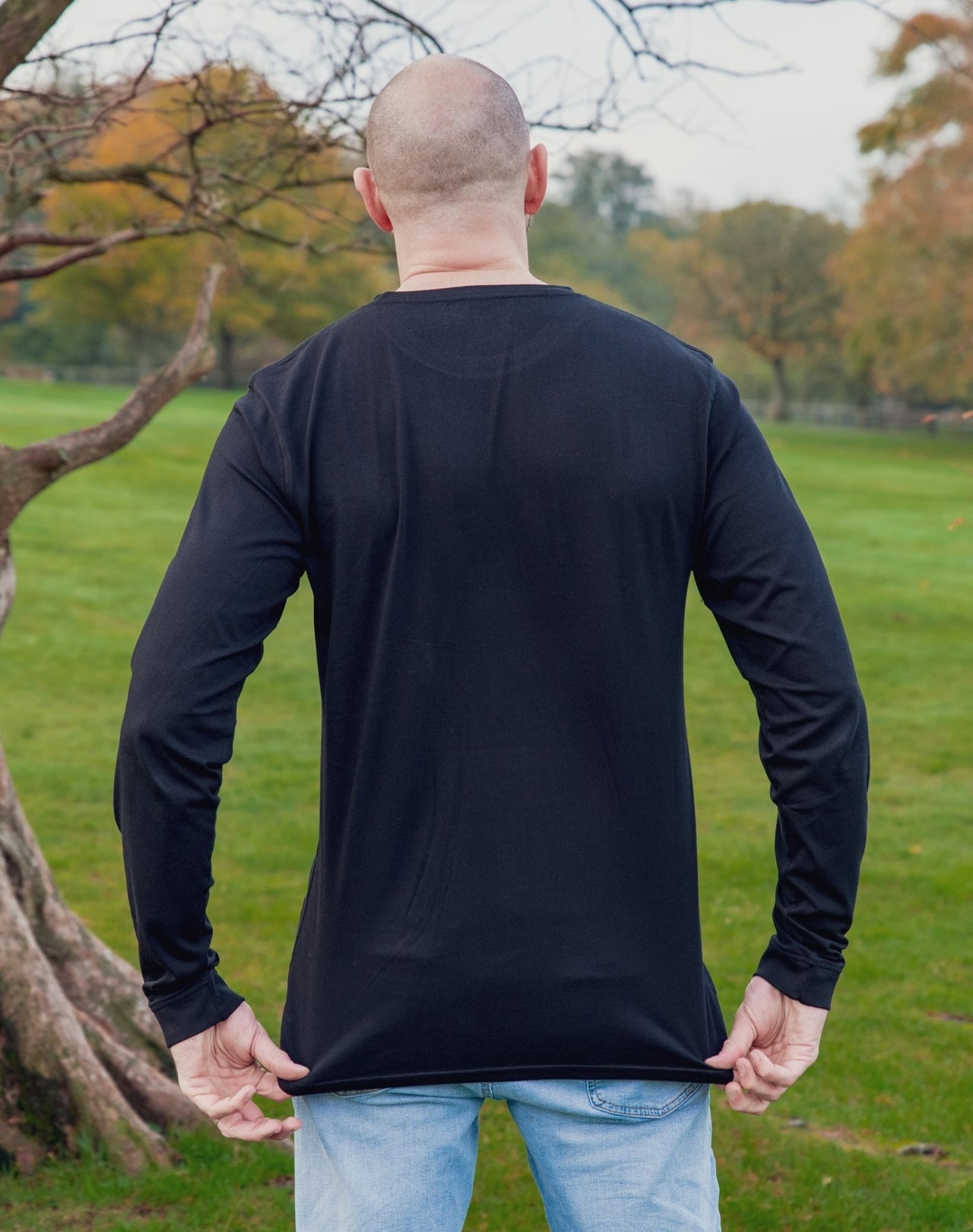 A shot from behind of a tall athletic guy wearing a long sleeve black tall t-shirt.