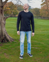 Thumbnail for A head to toe shot of a tall athletic guy in a park wearing a black long sleeve tall t-shirt, looking to the right
