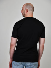 Thumbnail for A shot from behind of a tall and slim guy in the studio and wearing a black XL tall slim t-shirt.